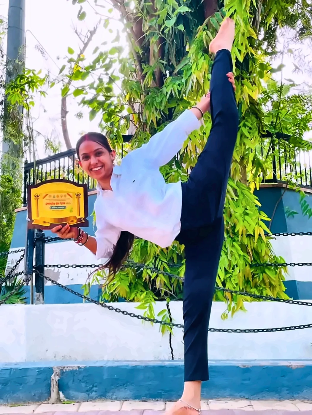 Latika, haath mein award liye, standing split asana mein