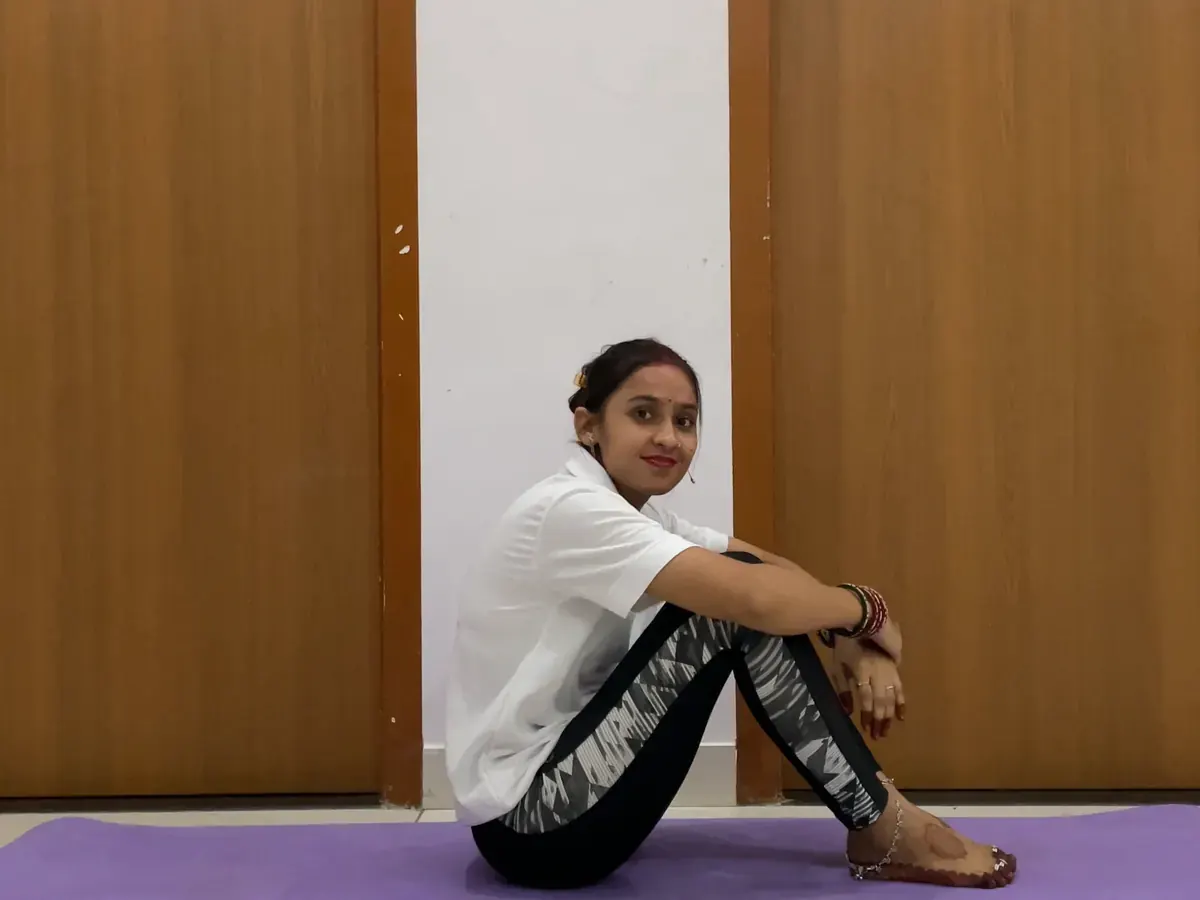 Latika yoga mat par aaram se ghutne pakad kar baithi hui