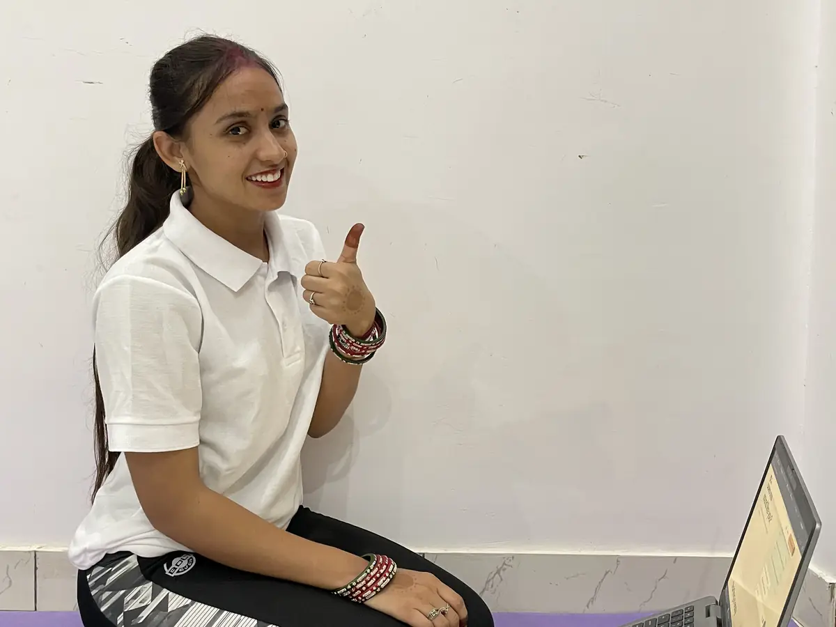 Latika yoga mat par laptop ke saath, thumbs up karte hue
