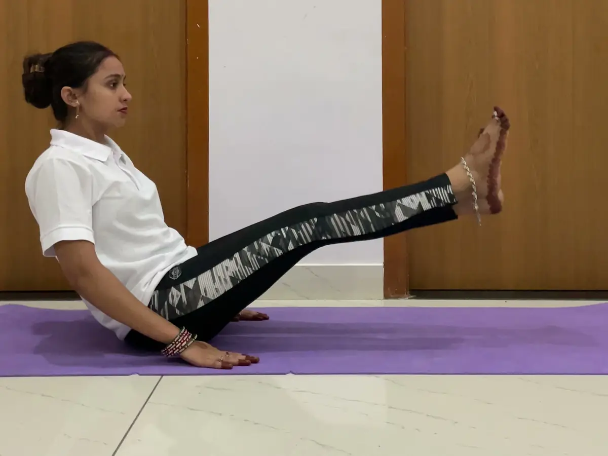 Latika seated on her mat raising a straight leg to strengthen the thigh